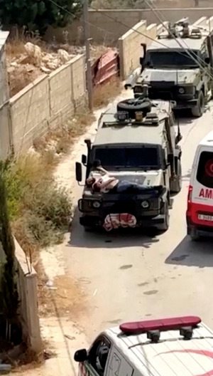 Israeli forces strap wounded Palestinian to jeep during raid
